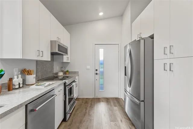 a kitchen with stainless steel appliances a refrigerator a sink and white cabinets