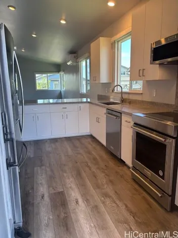 a large kitchen with stainless steel appliances granite countertop a stove a sink and a granite countertops with wooden floor