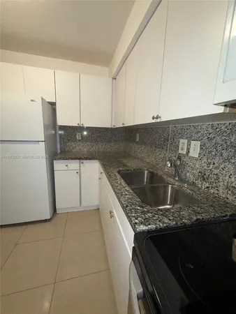 a kitchen with granite countertop a sink a stove and cabinets