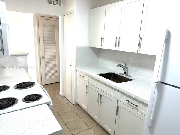 a kitchen with a sink a refrigerator and cabinets