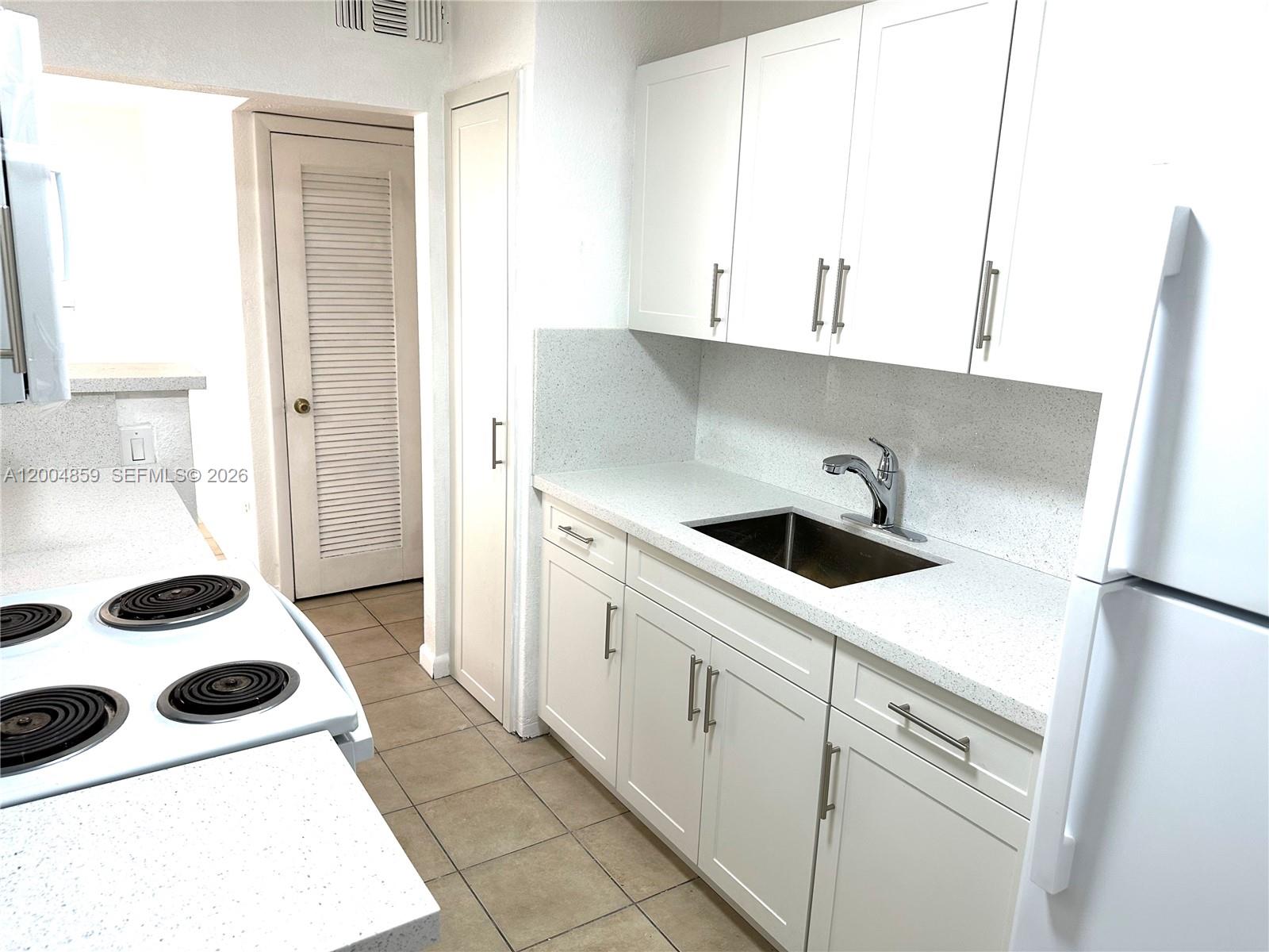 7256 Southwest 94th Place, Unit A4 Miami, FL 33173 - Photo 7 of 18 a kitchen with a sink a refrigerator and cabinets