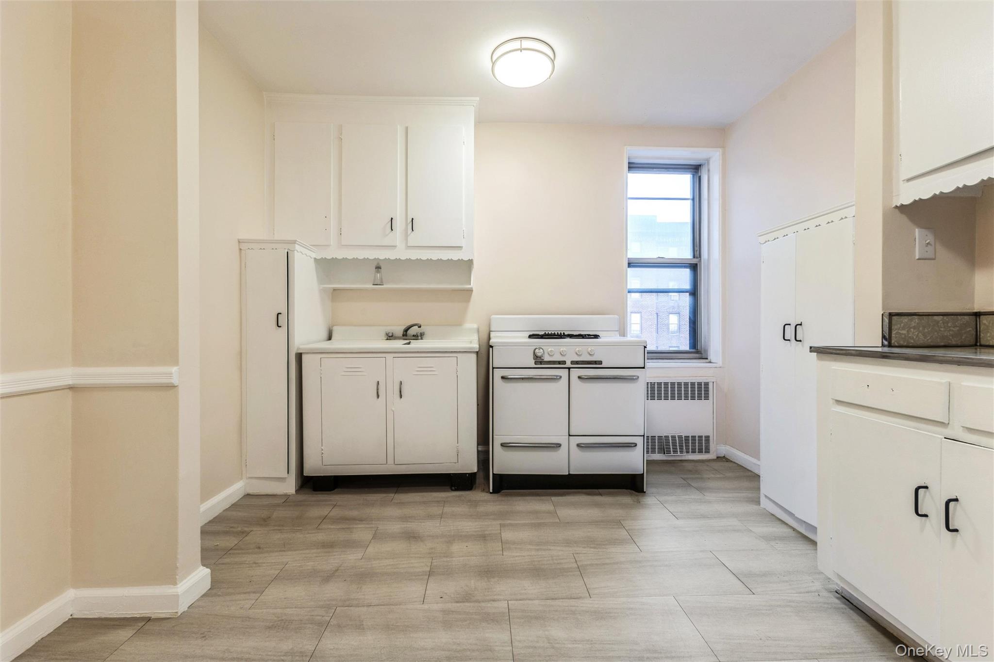 2232 Brigham Street, Unit EE4 Brooklyn, NY 11229 - Photo 7 of 16 Kitchen with range with two ovens, radiator heating unit, and white cabinets