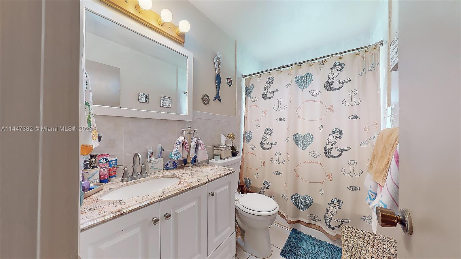 9815 Southwest 77th Street Miami, FL 33173 - Photo 19 of 30 a bathroom with a granite countertop sink a toilet and a shower curtain