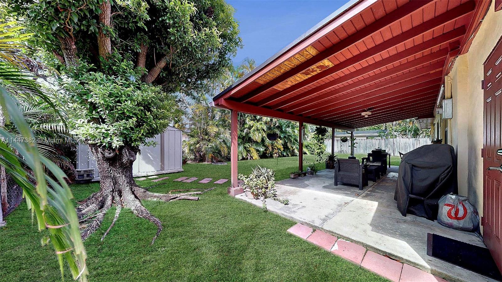 9815 Southwest 77th Street Miami, FL 33173 - Photo 25 of 30 a view of a backyard with table and chairs potted plants and a large tree