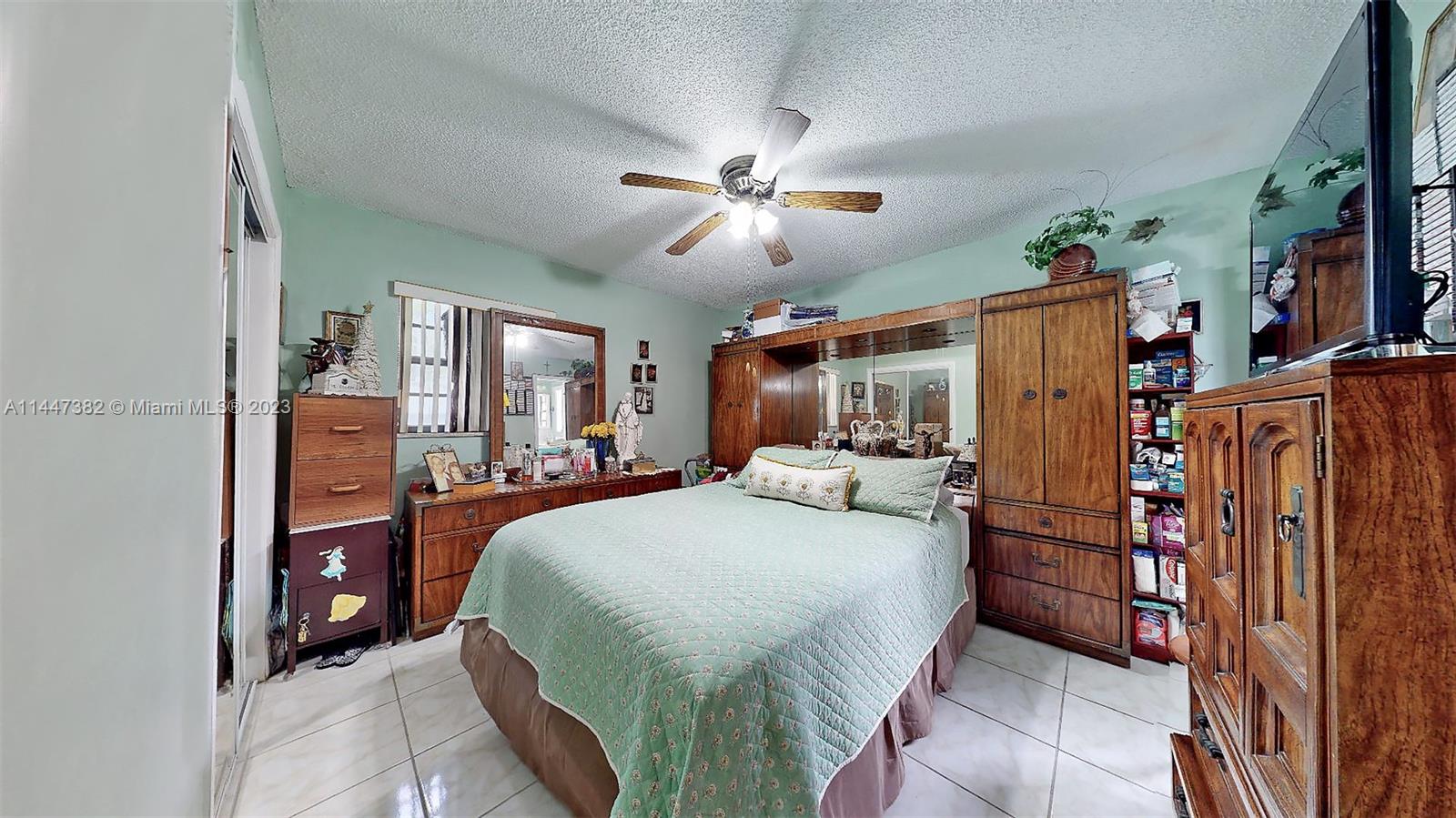 9815 Southwest 77th Street Miami, FL 33173 - Photo 4 of 30 a bedroom with a bed dresser and a flat tv screen