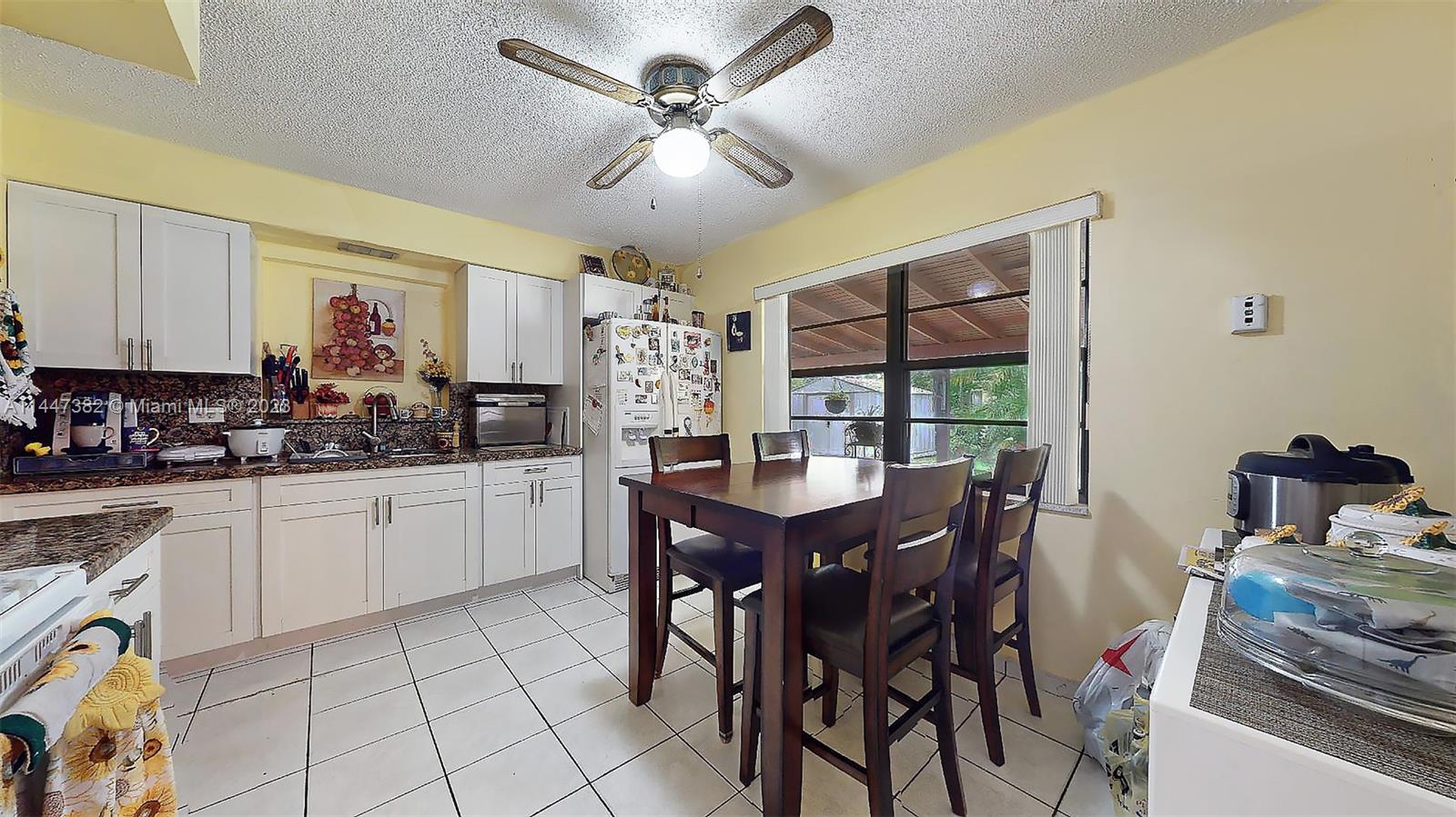 9815 Southwest 77th Street Miami, FL 33173 - Photo 10 of 30 a kitchen with stainless steel appliances granite countertop a stove a sink a dining table and chairs with wooden floor