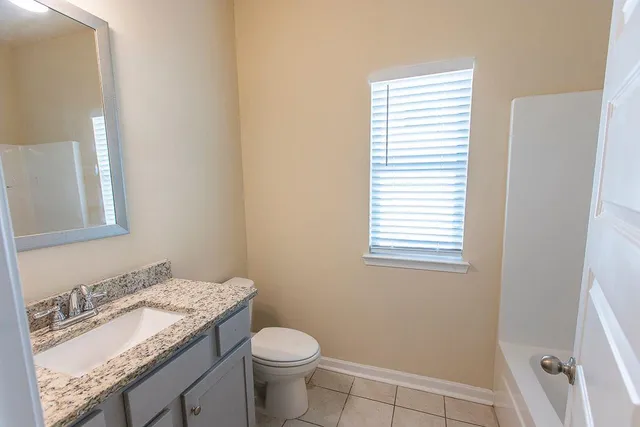 a bathroom with a granite countertop sink toilet and mirror