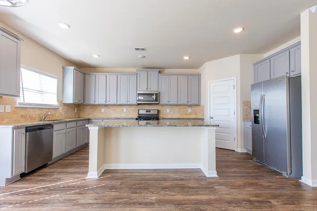 a kitchen with stainless steel appliances granite countertop a stove a sink and a refrigerator