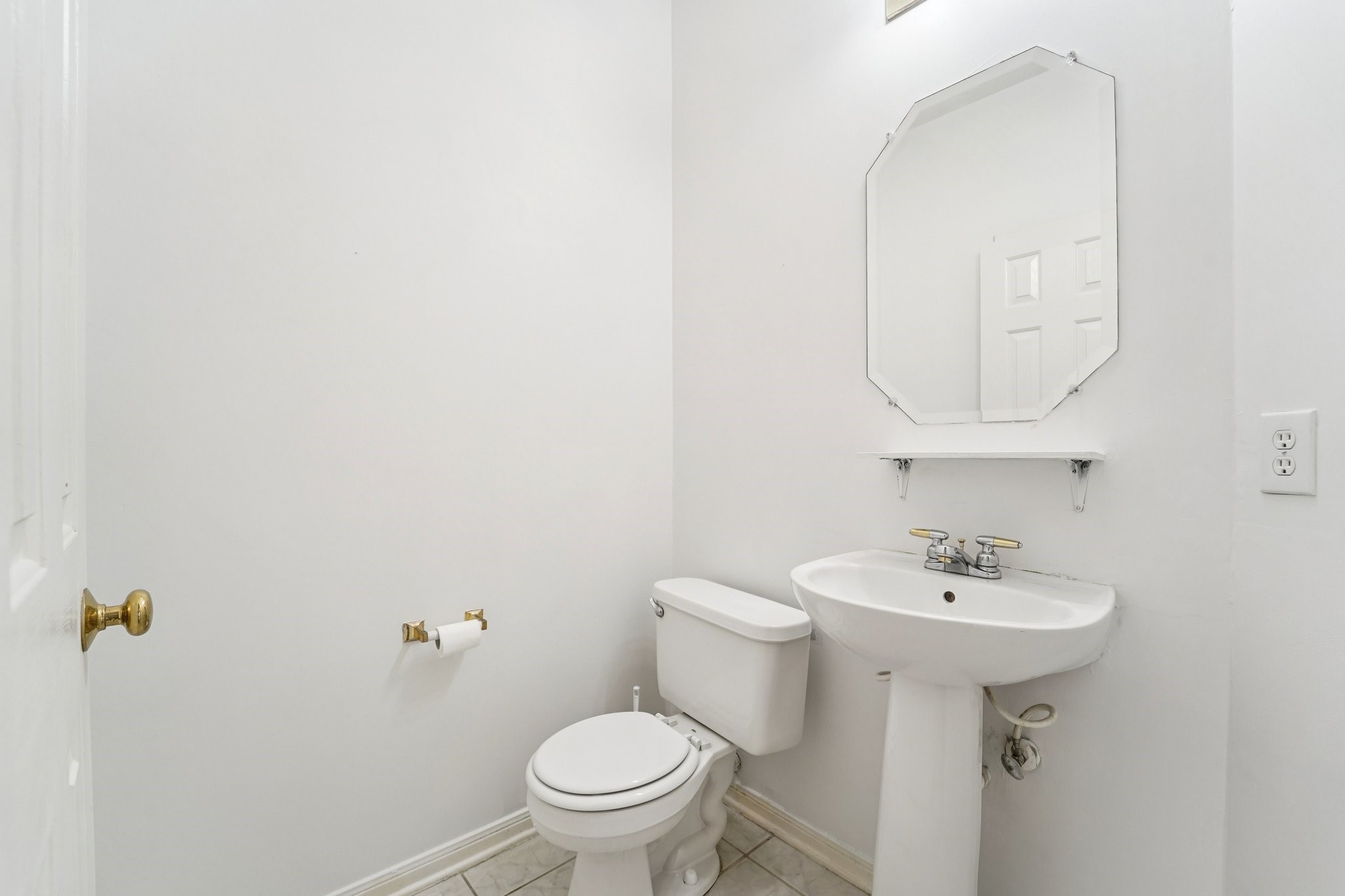 14420 Walters Road, Unit 55 Houston, TX 77014 - Photo 12 of 35 This photo shows a compact, bright bathroom with white walls. It features a toilet, a pedestal sink, and an octagonal mirror. The space is simple and well-lit, ideal for a guest or half-bath.