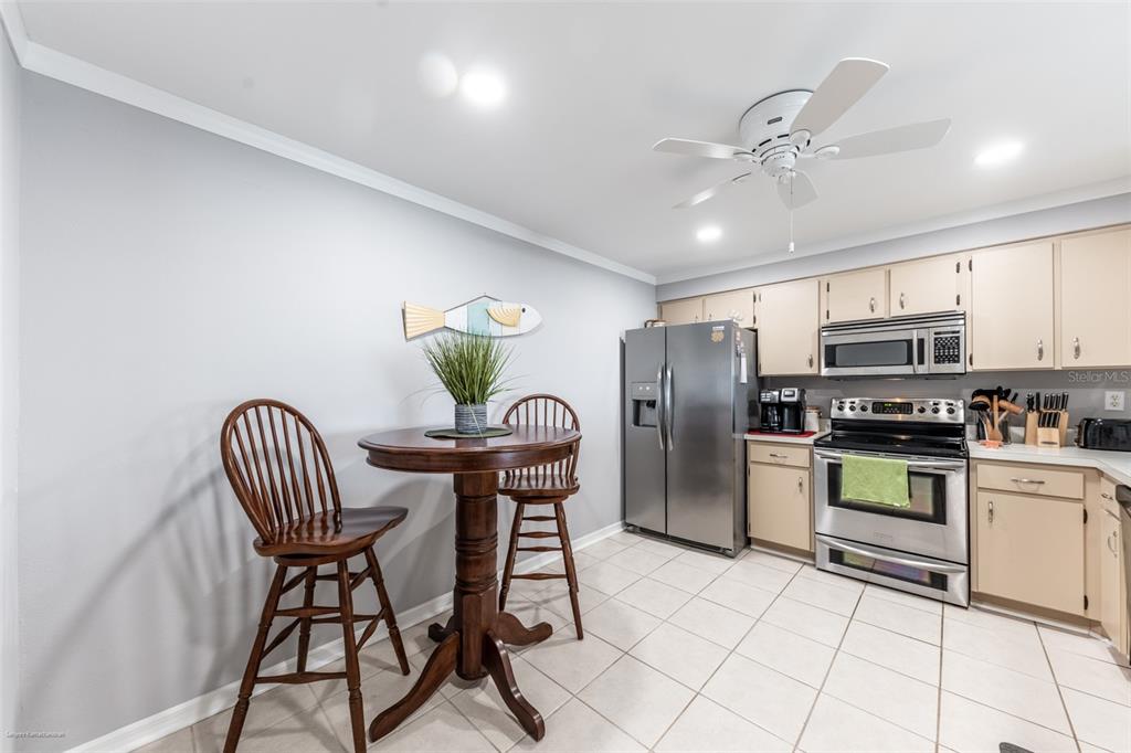 1477 Park Beach Circle, Unit 11 Punta Gorda, FL 33950 - Photo 14 of 49 a kitchen with stainless steel appliances kitchen island granite countertop a refrigerator a stove a microwave oven with a dining table and chairs