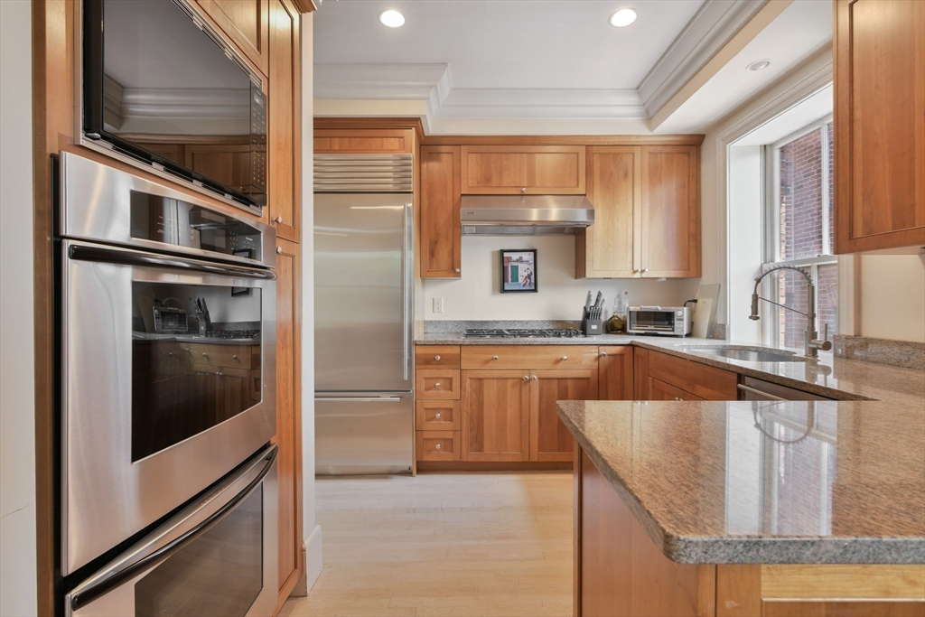 294 Commonwealth Avenue, Unit 2 Boston, MA 02115 - Photo 12 of 26 a kitchen with stainless steel appliances granite countertop a refrigerator a stove and a sink with wooden cabinets