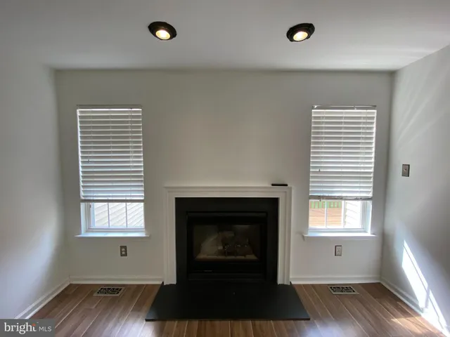 an empty room with wooden floor a fireplace and windows