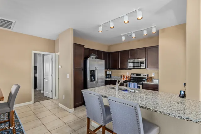 a kitchen with stainless steel appliances granite countertop a refrigerator a stove a sink a dining table and chairs