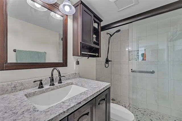 a bathroom with a granite countertop sink a mirror a vanity and a shower