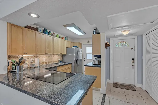 a view of a kitchen with kitchen island granite countertop a refrigerator and a sink