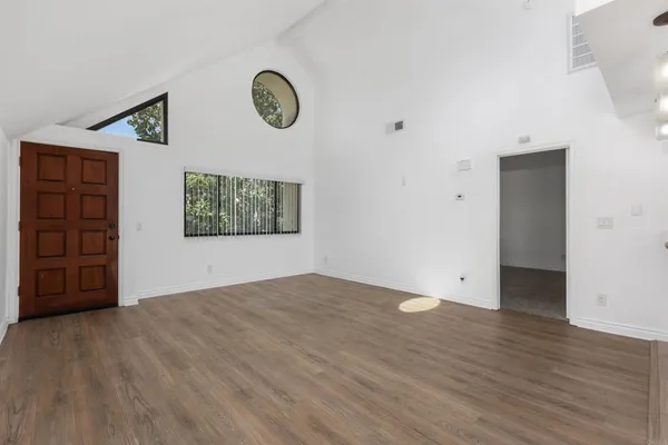 a view of a refrigerator in kitchen and an empty room