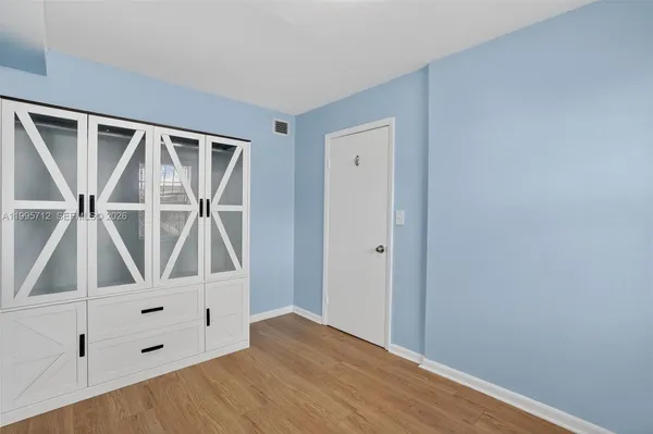 a view of an empty room with wooden floor and white walls