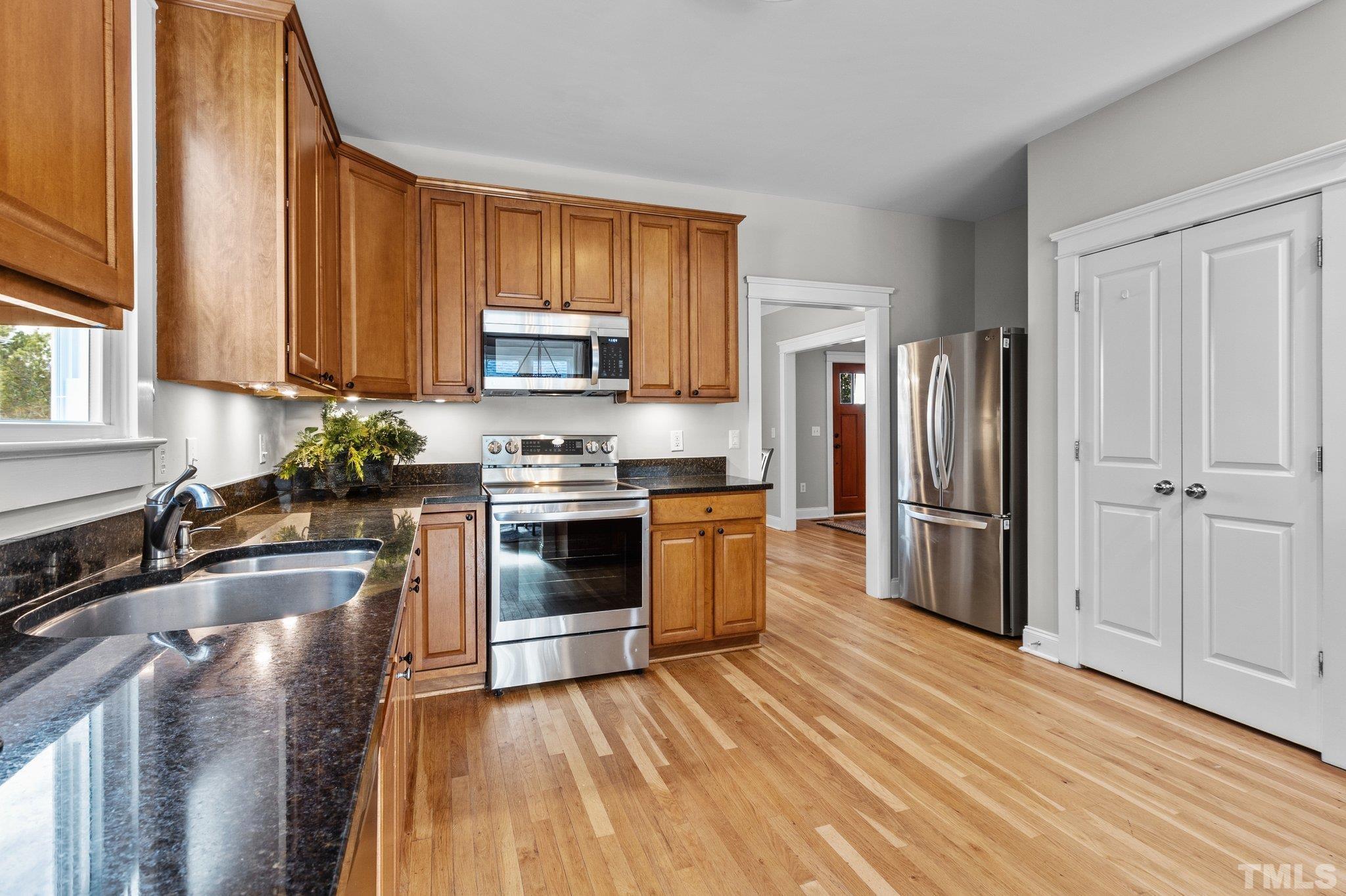 145 Kingsport Road Holly Springs, NC 27540 - Photo 11 of 42 a kitchen with granite countertop wooden floors stainless steel appliances a sink and a window