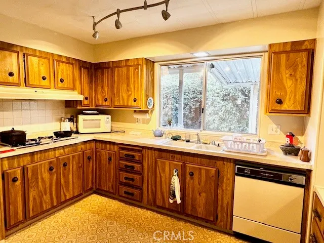 a kitchen with stainless steel appliances granite countertop wooden cabinets a sink and dishwasher with wooden floor