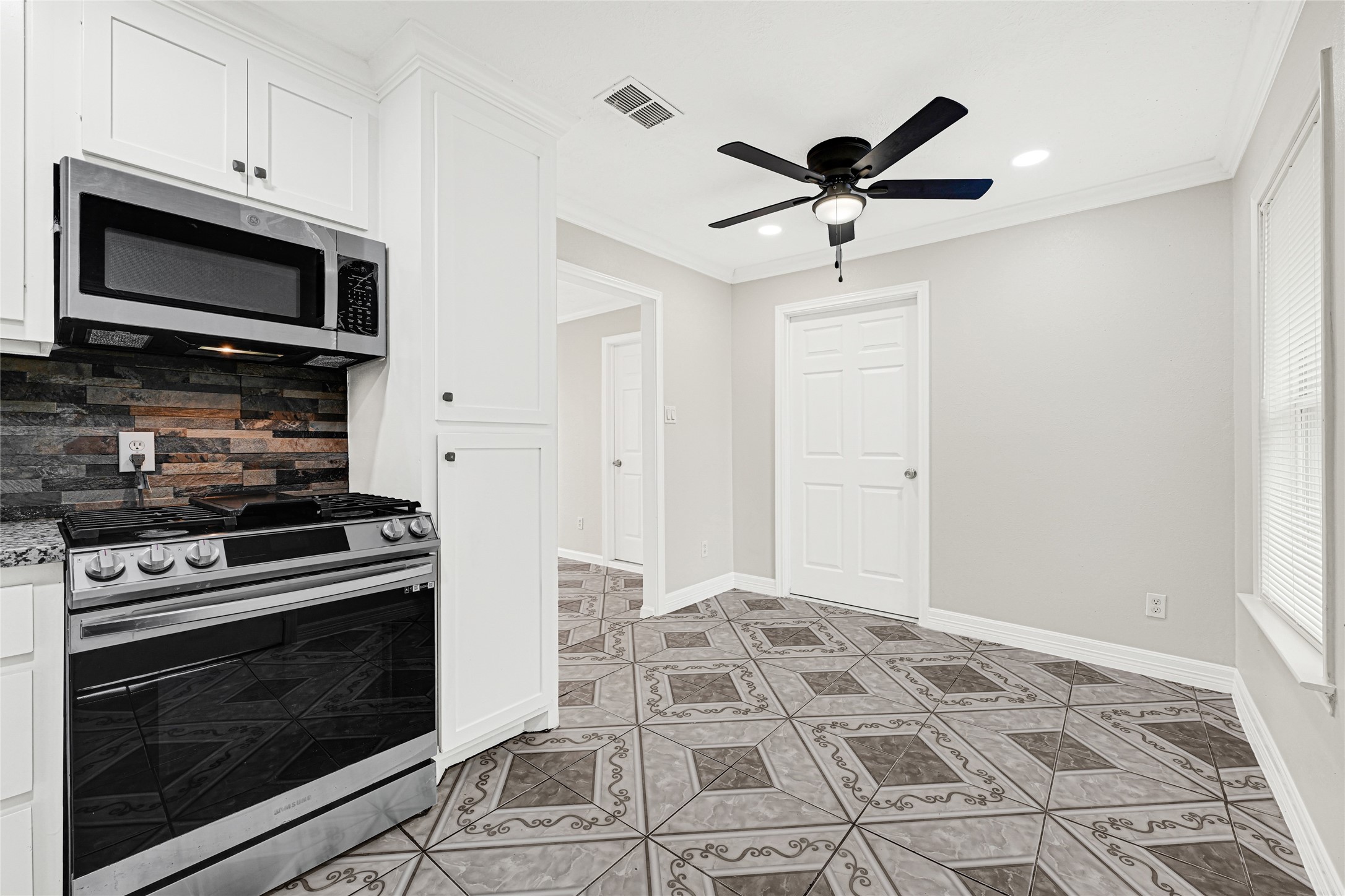 2207 Raymond Street Pasadena, TX 77506 - Photo 9 of 21 a kitchen with stainless steel appliances a stove a microwave and white cabinets