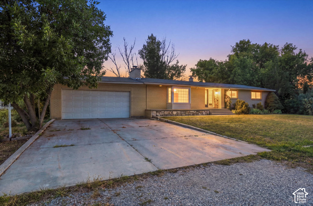 15295 North 5400th Street West Riverside, UT 84334 - Photo 1 of 54 Ranch-style exterior featuring a light-toned brick facade, an attached two-car garage, a concrete driveway, and a front lawn
