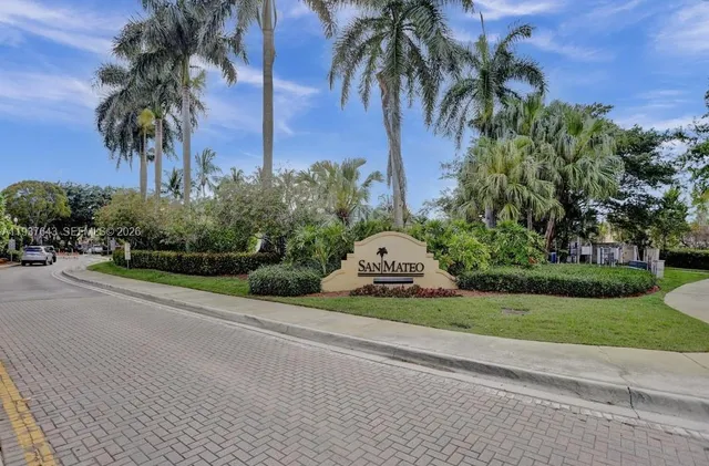 a view of a house with a yard and palm trees