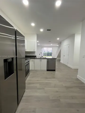 a kitchen with stainless steel appliances kitchen island granite countertop a refrigerator and a sink