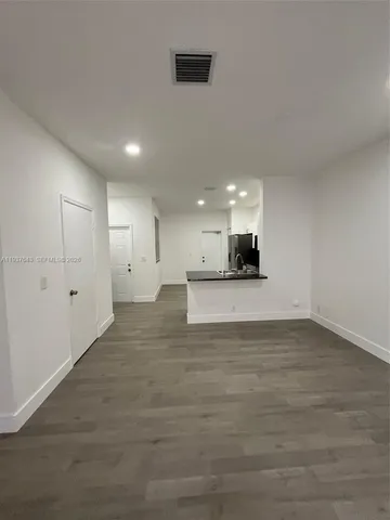 a view of an empty room and kitchen view