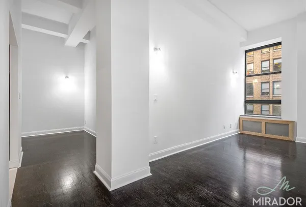 an empty room with wooden floor cabinet and windows