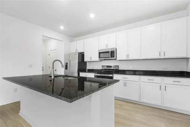 a kitchen with stainless steel appliances granite countertop a refrigerator a sink a stove and oven