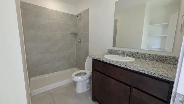 a bathroom with a granite countertop sink a toilet and shower