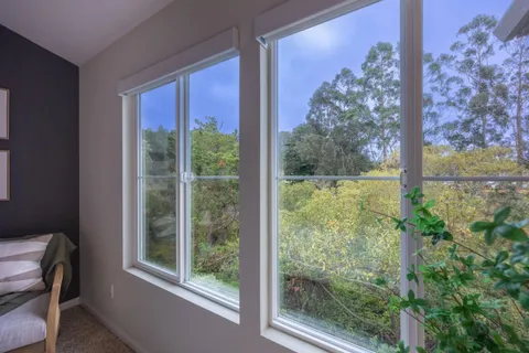 a view of a room that has a large window and front red door