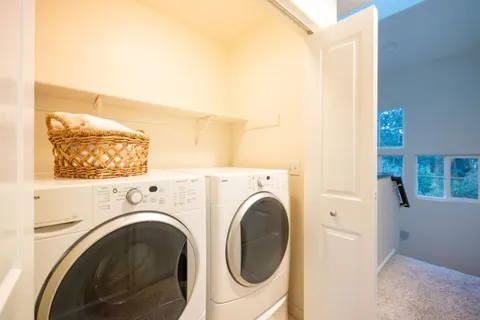 a view of washer and dryer with bathroom in the background