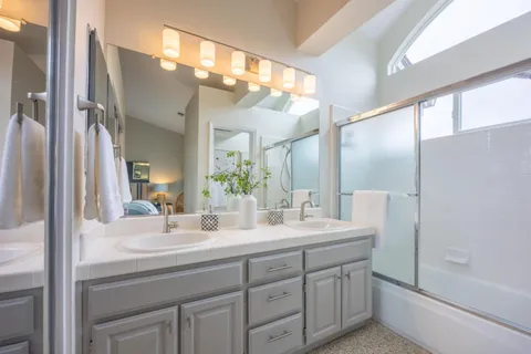 a bathroom with a double vanity sink mirror and shower
