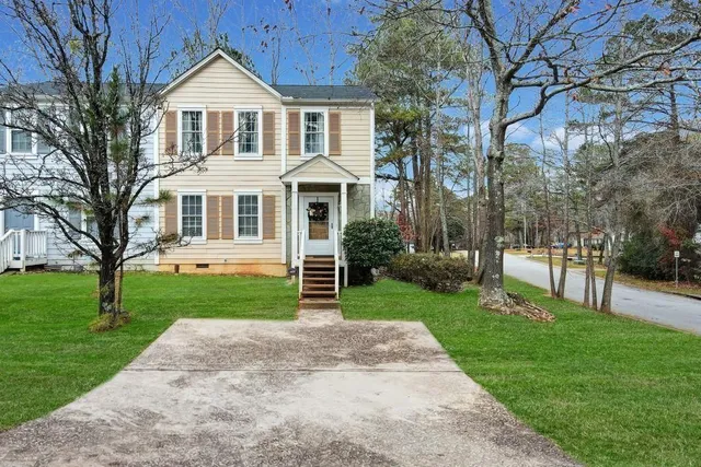 a front view of a house with a yard and trees