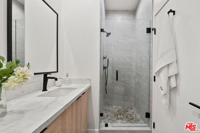 a bathroom with a granite countertop sink a mirror and shower
