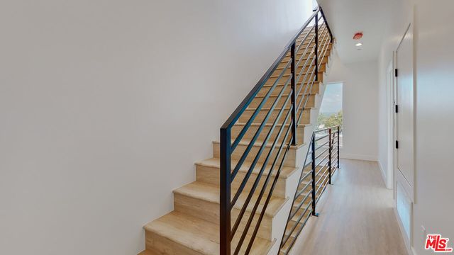 a view of staircase with wooden floor and white walls