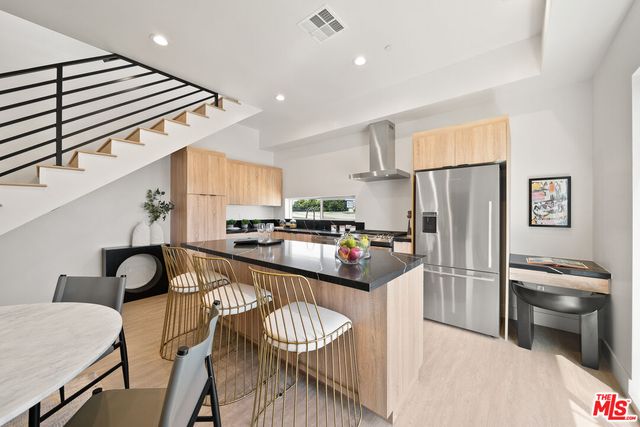 a kitchen with stainless steel appliances granite countertop a refrigerator a stove and a sink