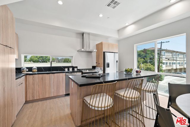 a kitchen with stainless steel appliances granite countertop a kitchen island a stove a sink a dining table and chairs