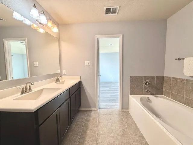 a bathroom with a bathtub shower sink mirror and toilet
