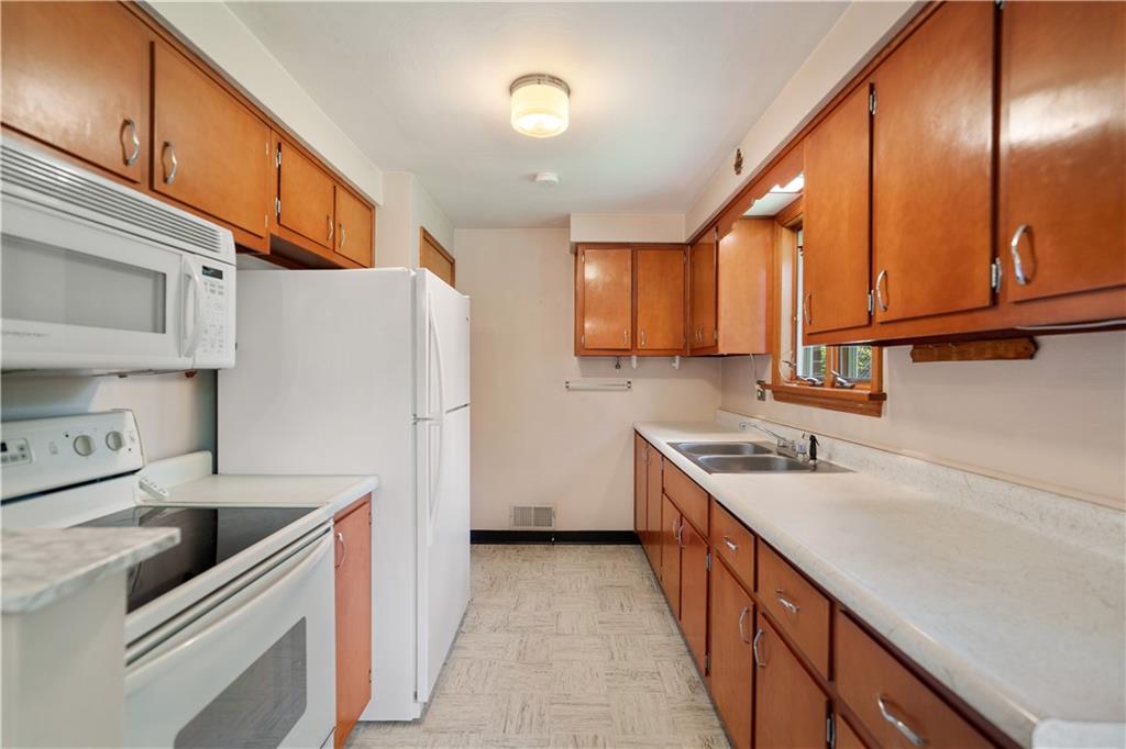 77 Observatory Street Manor, PA 15665 - Photo 11 of 25 a kitchen with a sink a refrigerator and cabinets