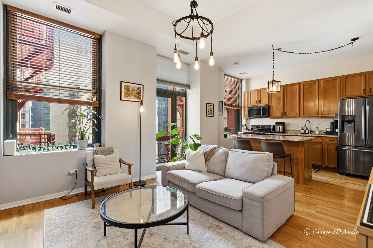 208 West Washington Street, Unit 1007 Chicago, IL 60606 - Photo 9 of 18 a living room with stainless steel appliances furniture a chandelier and a kitchen view