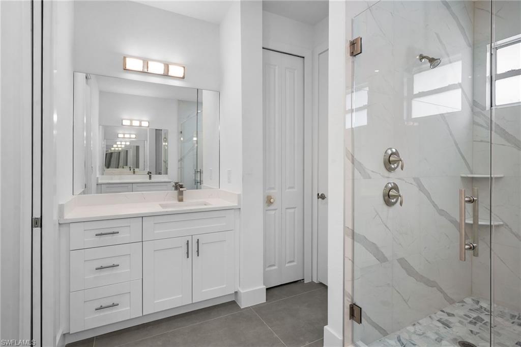 2712 40th Avenue Southeast Naples, FL 34117 - Photo 20 of 41 a bathroom with a granite countertop sink a mirror and a shower