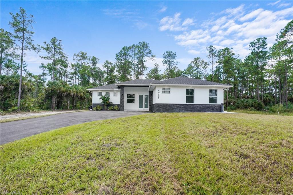 2712 40th Avenue Southeast Naples, FL 34117 - Photo 2 of 41 a front view of house with yard and trees in the background