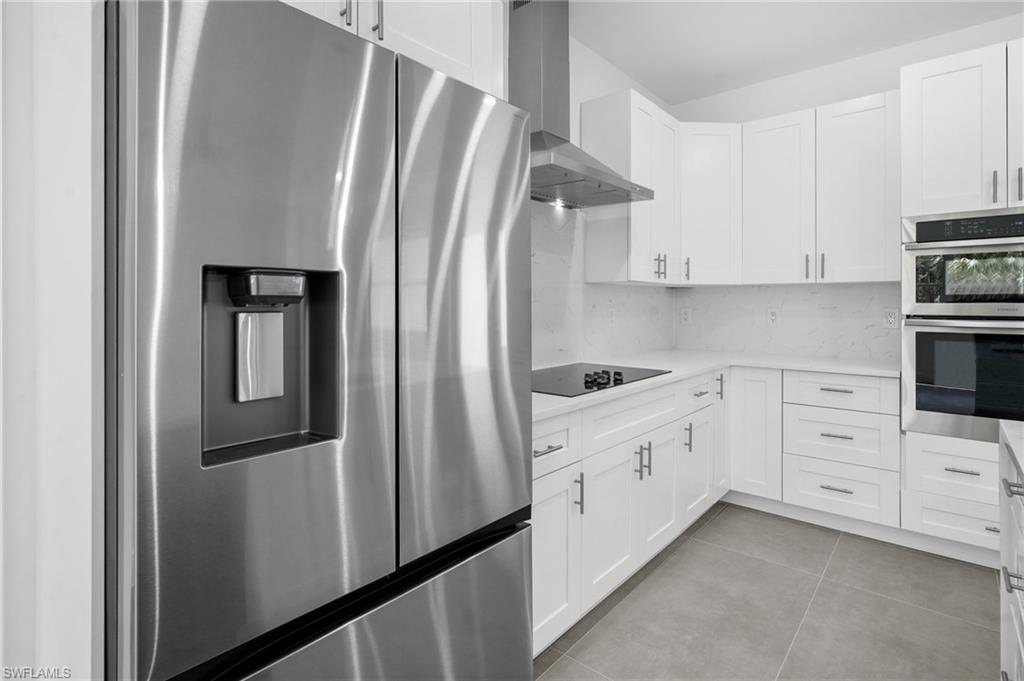 2712 40th Avenue Southeast Naples, FL 34117 - Photo 8 of 41 a kitchen with white cabinets and stainless steel appliances
