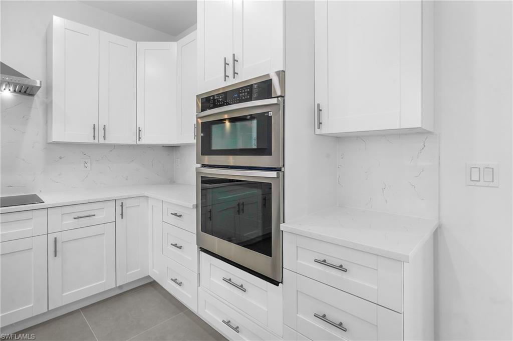 2712 40th Avenue Southeast Naples, FL 34117 - Photo 9 of 41 a kitchen with white cabinets and stainless steel appliances
