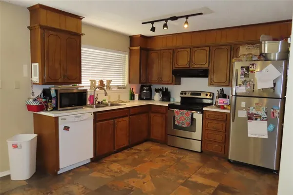 a kitchen with stainless steel appliances granite countertop a refrigerator a stove a sink and a microwave