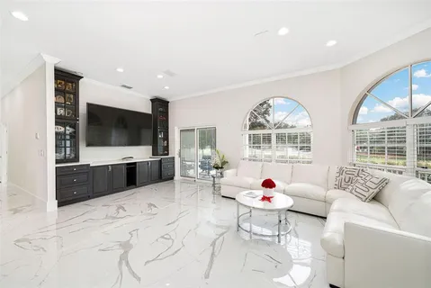 a living room with furniture a flat screen tv and a floor to ceiling window