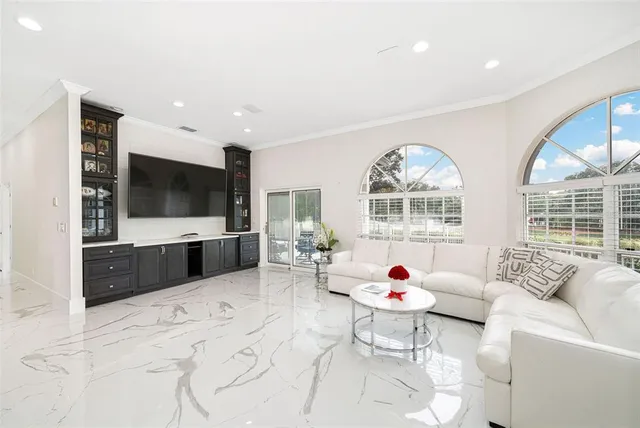 a living room with furniture a flat screen tv and a floor to ceiling window