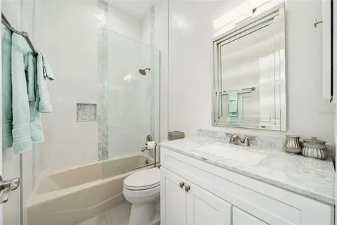 a bathroom with a granite countertop sink a toilet and shower
